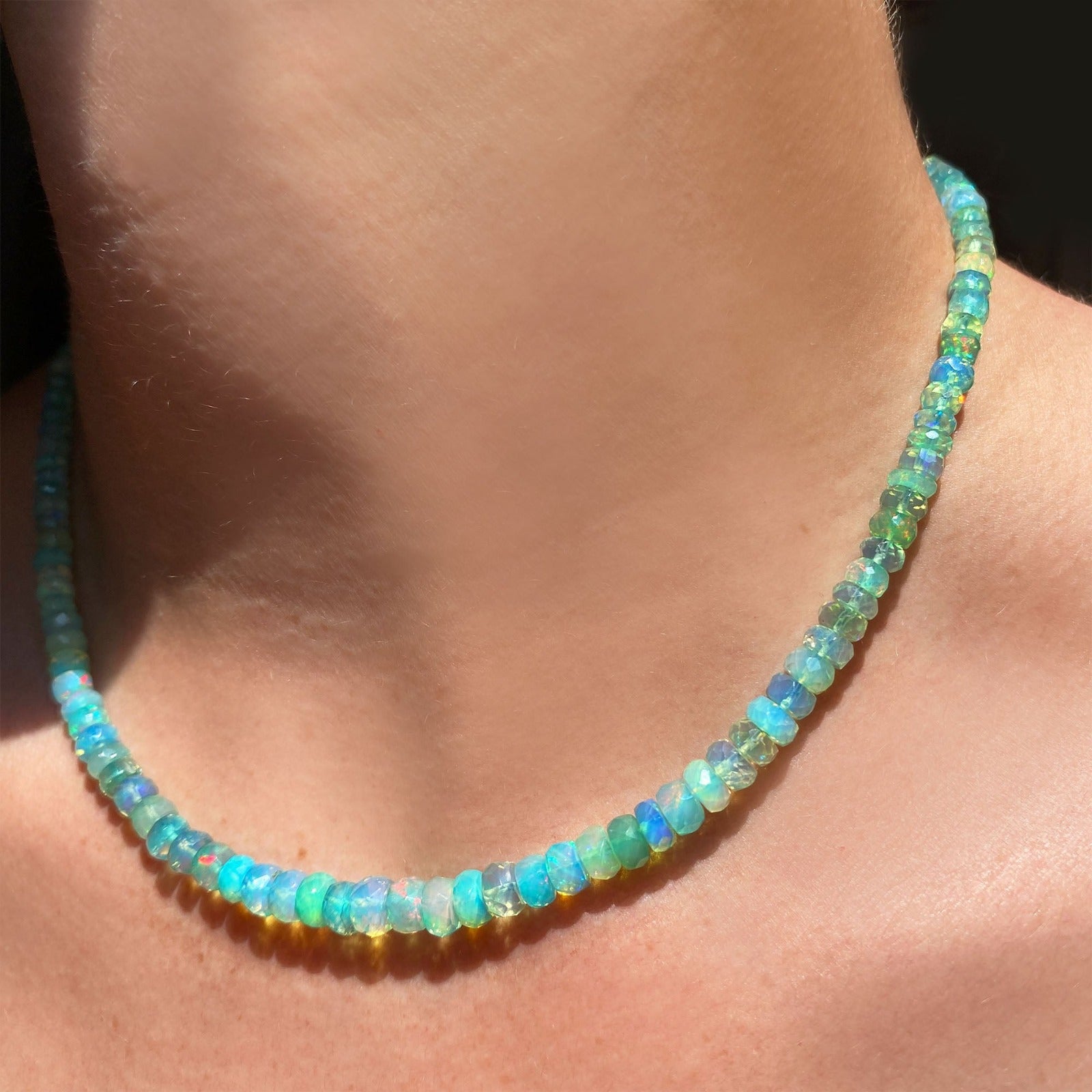 Shimmering beaded necklace made of faceted opals in shades of Blue, Teal, green and pale blue on a gold linking ovals clasp Styled on a neck