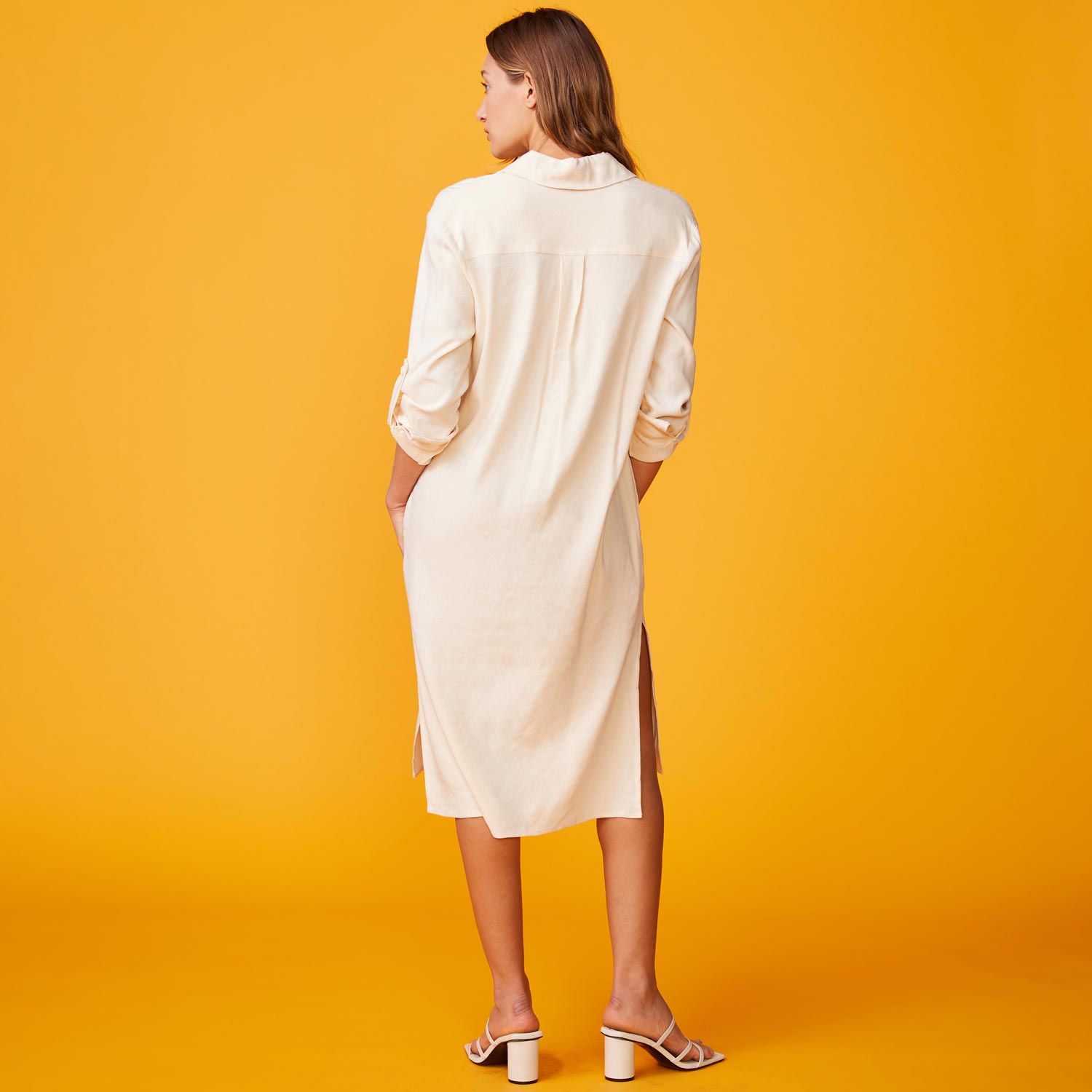 Back view of model wearing the linen shirt dress in buttercream.