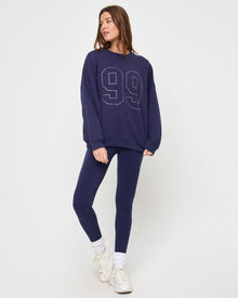 Front view of the LSPACE Legend Sweatshirt in midnight blue on a model against a light background, showing the cropped oversized sweatshirt with rhinestone graphic detail.