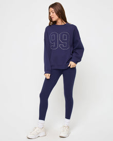 Angled view of the LSPACE Legend Sweatshirt in midnight blue on a model against a light background, showing the rhinestone graphic detail.