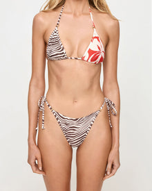 close up view of woman wearing a patterned bikini against a plain background