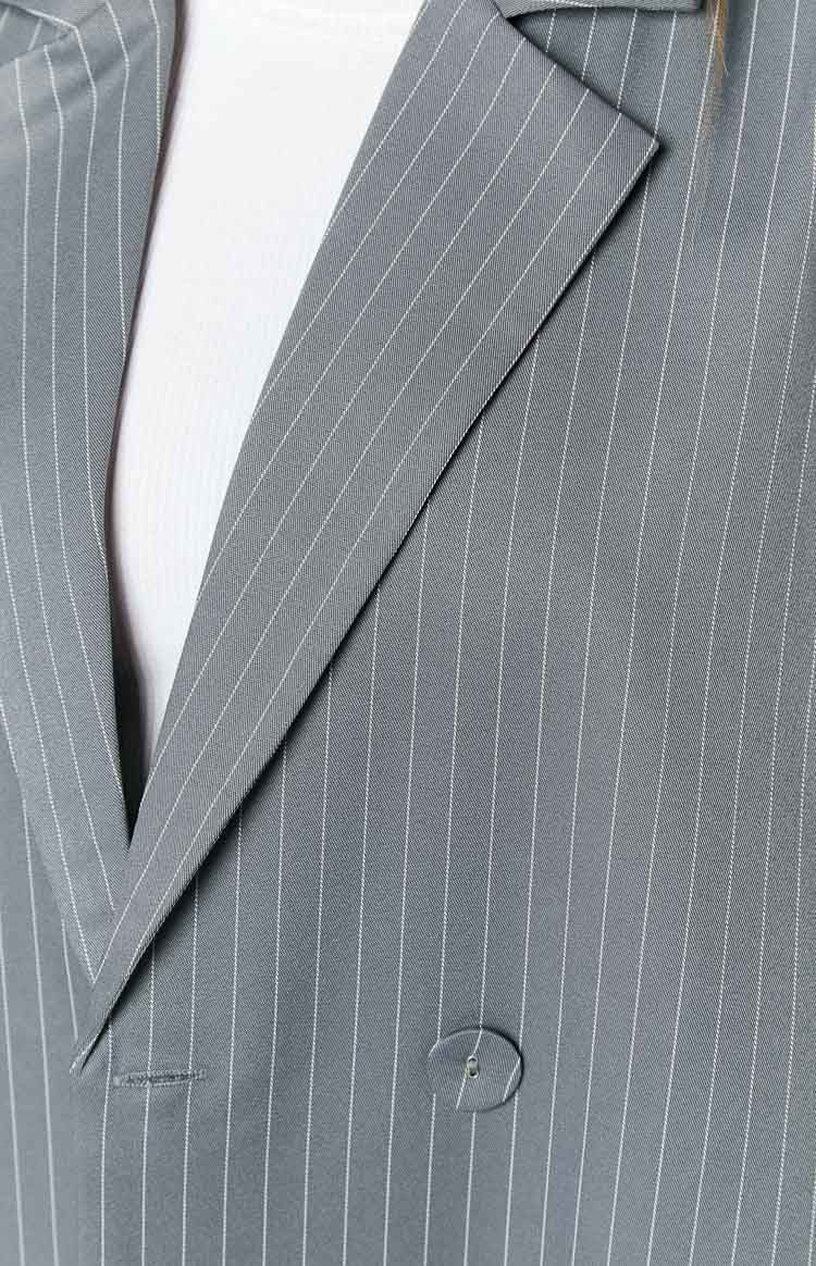 Close-up of the grey pinstriped blazer showing a notched lapel, button, and buttonhole