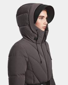 A woman in the Rudsak ENZAH - 8124692 Grey down puffer jacket with black drawstrings and a black brimmed hat is shown in profile against a plain white background.