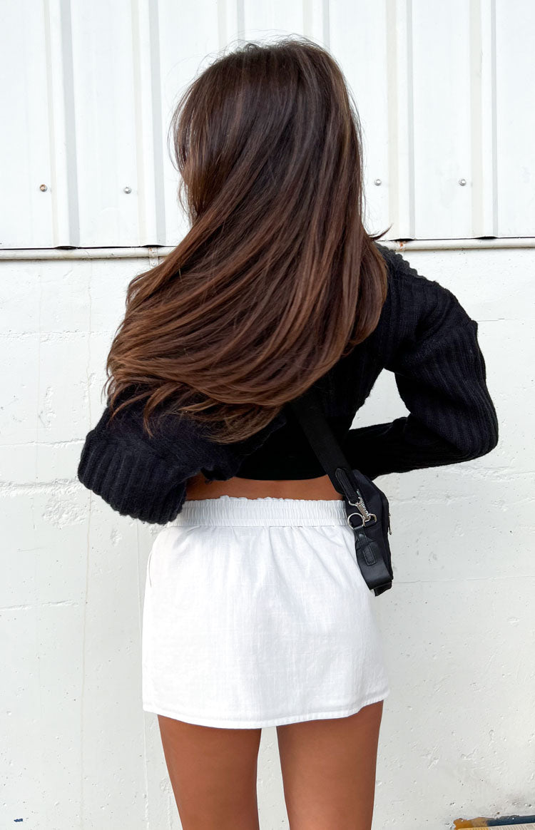 Back view of a white mini skirt featuring a ruched elastic waistband and a subtle textured fabric
