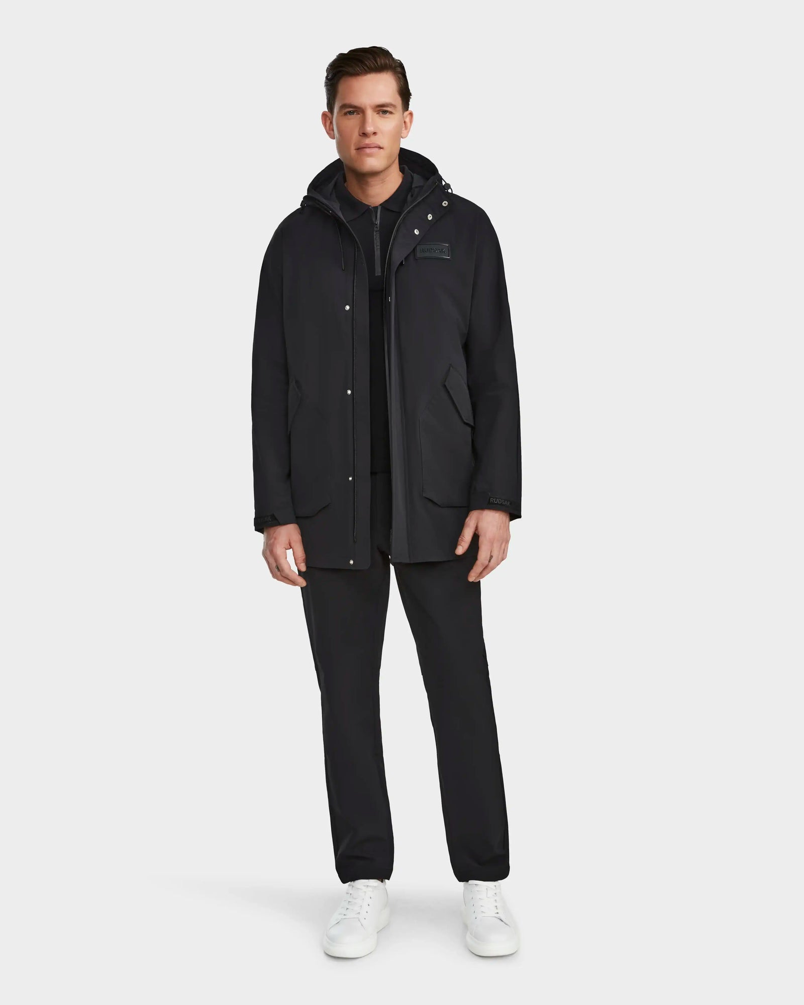 A man wearing the Rudsak IAN - 6124009 Black rainwear jacket looks sharp and prepared for any weather.