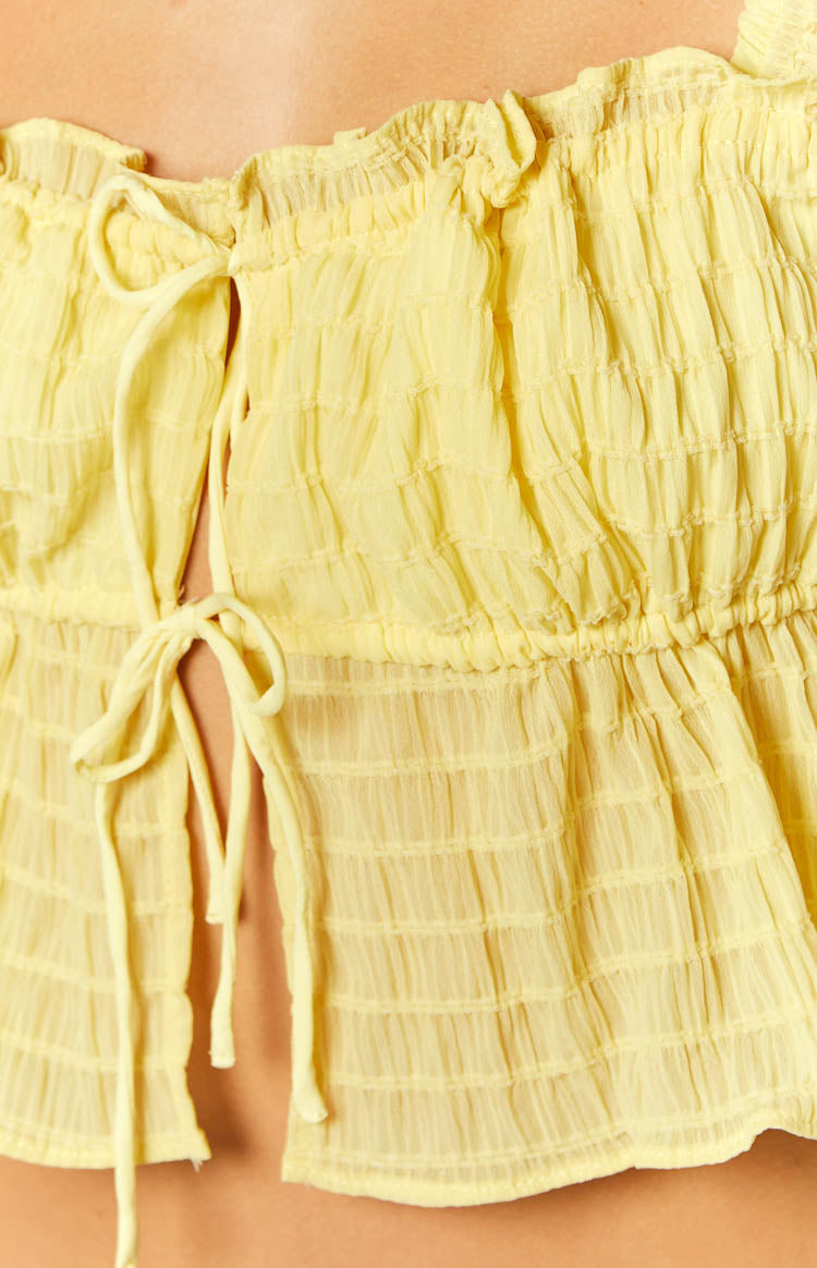 Rear view of a yellow smocked crop top with elasticated shirred fabric and ruffled shoulder straps