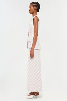 Sleeveless cream vest with vertical pleats and patch pocket, styled with gingham maxi skirt and white platform shoes.
