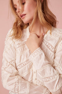 Long sleeve button down top with a v-neckline and diagonal laces for added texture detailing.