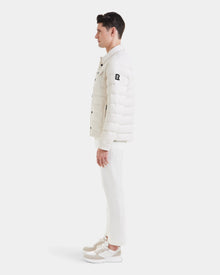 A man in profile wears the Rudsak AZIEL - M124521 Vanilla duck down jacket with white pants and sneakers, posed against a plain white background.