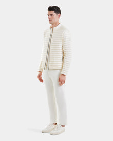 A man stands in the Rudsak REYMOND - M125013 Iceland off-white recycled nylon quilted down jacket, paired with white pants and sneakers against a plain white background, facing slightly left with hands relaxed at his sides.