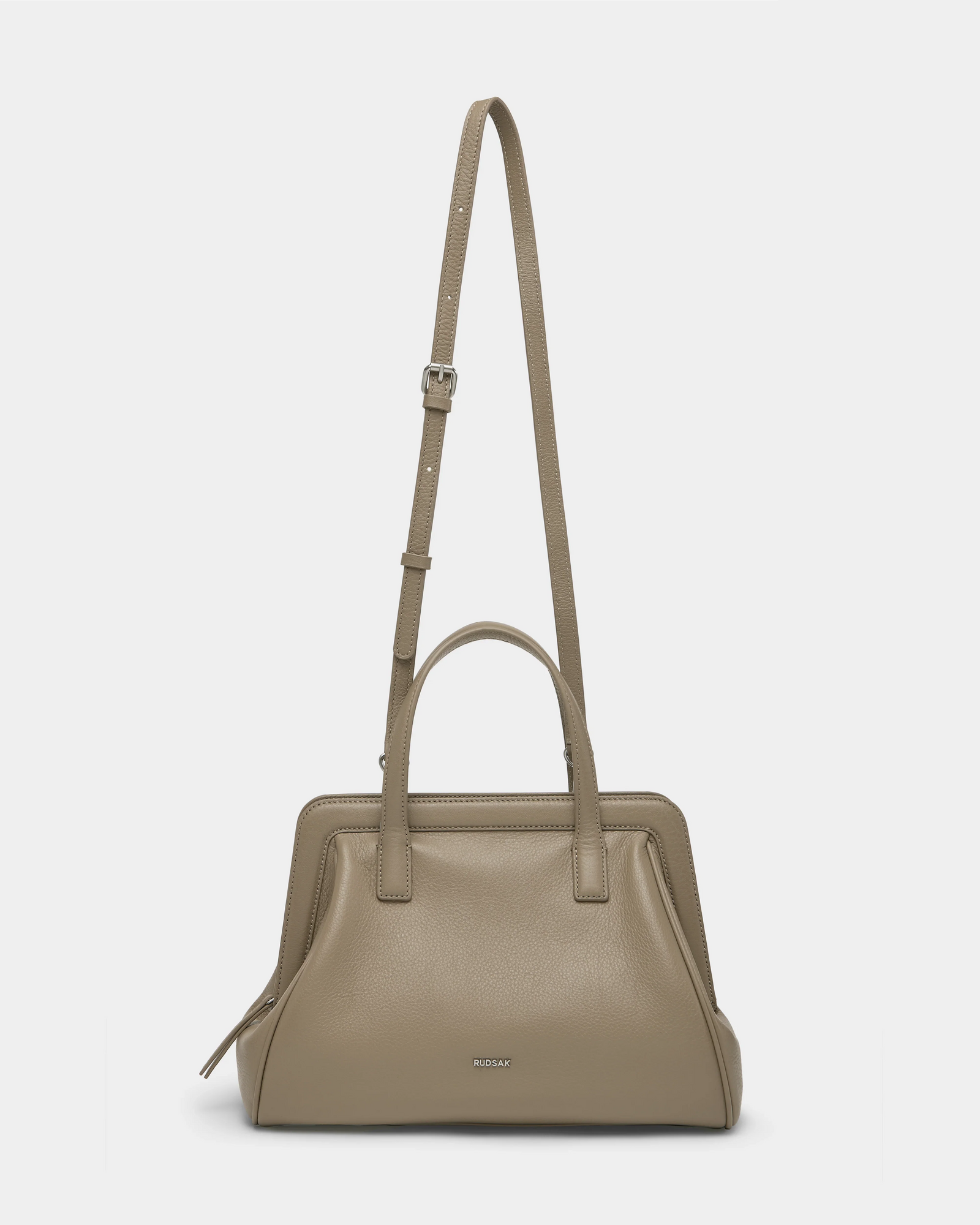 The Rudsak TAULLA - 8325002 Almond is a taupe pebble leather women’s satchel with double handles and a removable shoulder strap, subtle silver hardware, a small logo front, and a roomy interior for daily essentials.