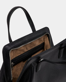 A close-up of the Rudsak TAULLA - 8325002 Black women’s pebble leather satchel with its top zipper open, revealing a spacious interior lined with brown suede and an inner zippered pocket.