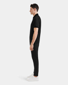 A man wearing the WALTER - 6524531 Black/Black premium cotton polo by Rudsak and black pants.