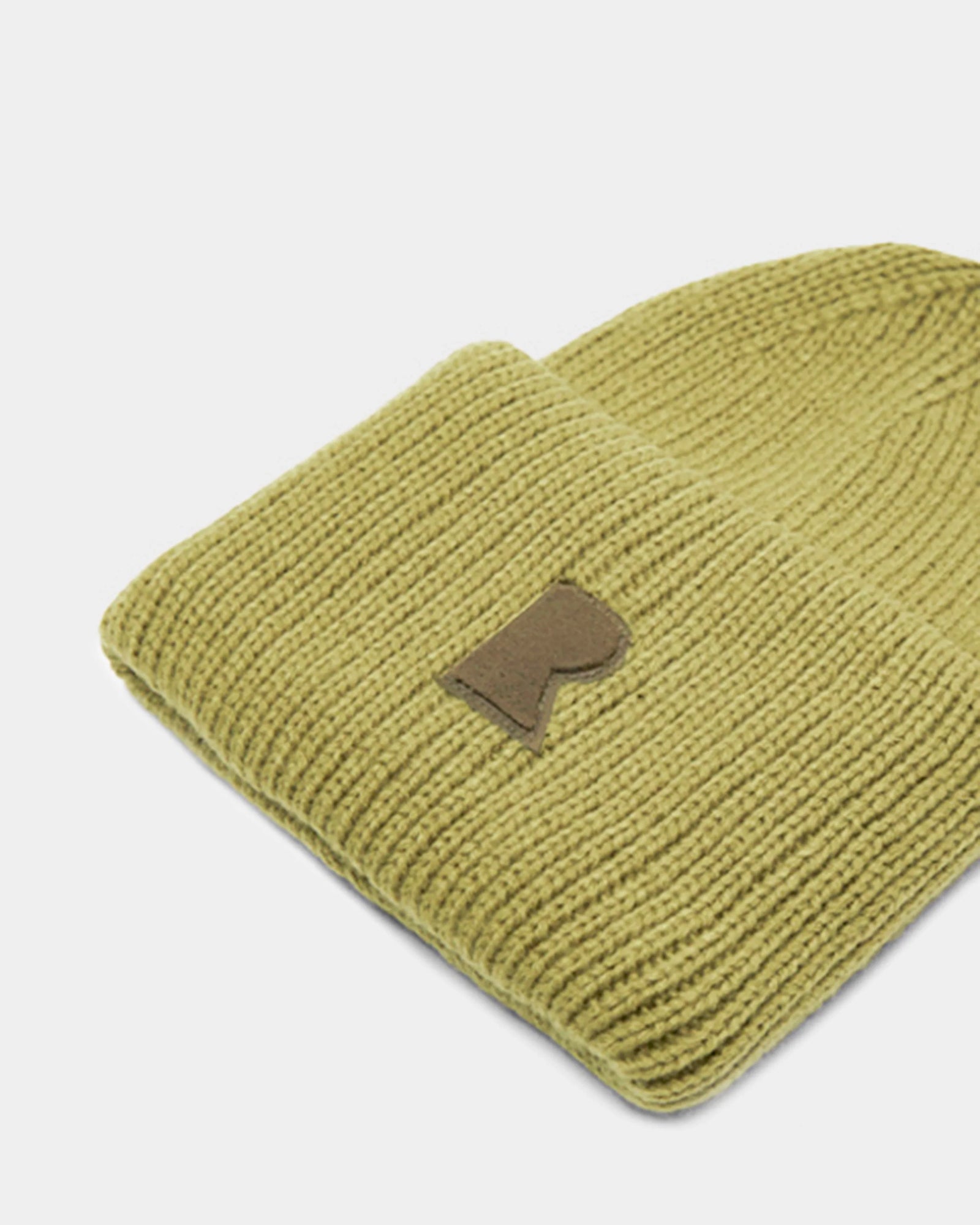 A close-up of the Rudsak MURRAY - U423503 Light Olive unisex ribbed knit beanie, featuring a folded brim and small brown patch with a stylized R logo on the front—an urban winter essential.