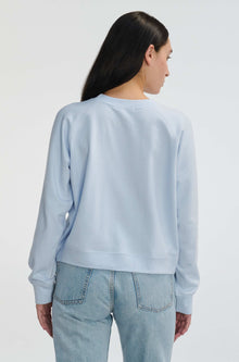 Person wearing a light blue sweatshirt and jeans on a white background