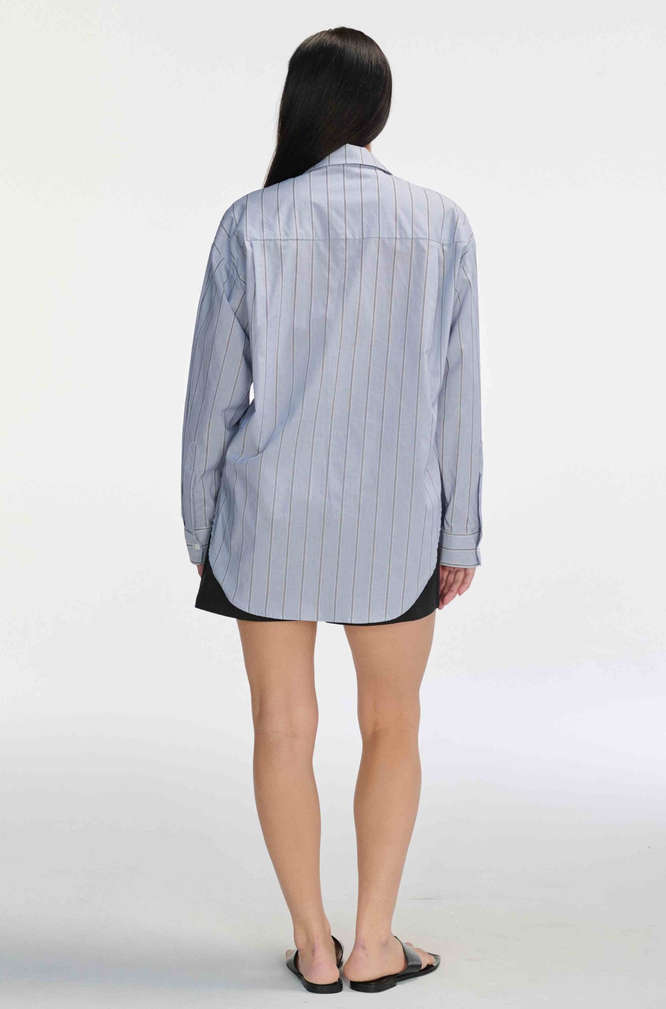 Woman wearing a black and navy striped shirt with black shorts against a light grey background