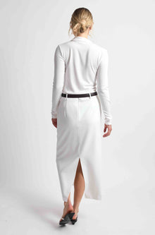 Woman wearing a white button up top with a white skirt and brown belt