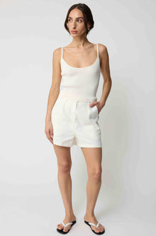 Woman wearing a white tank top and white linen shorts