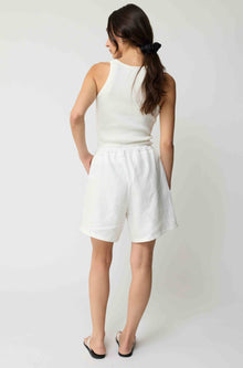 Woman wearing white linen shorts and a white tank top