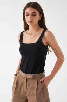 Woman wearing a black square tank top and brown pants