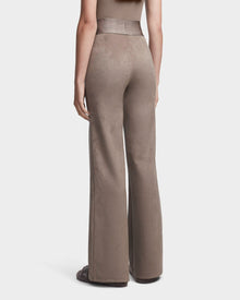 A person is seen from the back wearing Rudsaks SEDONA - 8523541 Cement high-waisted faux suede flare joggers, styled with brown shoes and a sleeveless top.