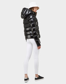 A person wearing the Excluded MARE - 8121011 BLACK ultra-light puffer jacket, white leggings, black sneakers, and a white bucket hat stands facing backward and glancing over their shoulder against a light grey background.