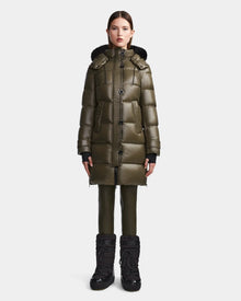 A woman stands facing forward wearing the Rudsak MEYA S - L123521 Light Olive women's down puffer coat, styled with matching green pants and black winter boots against a plain white background.