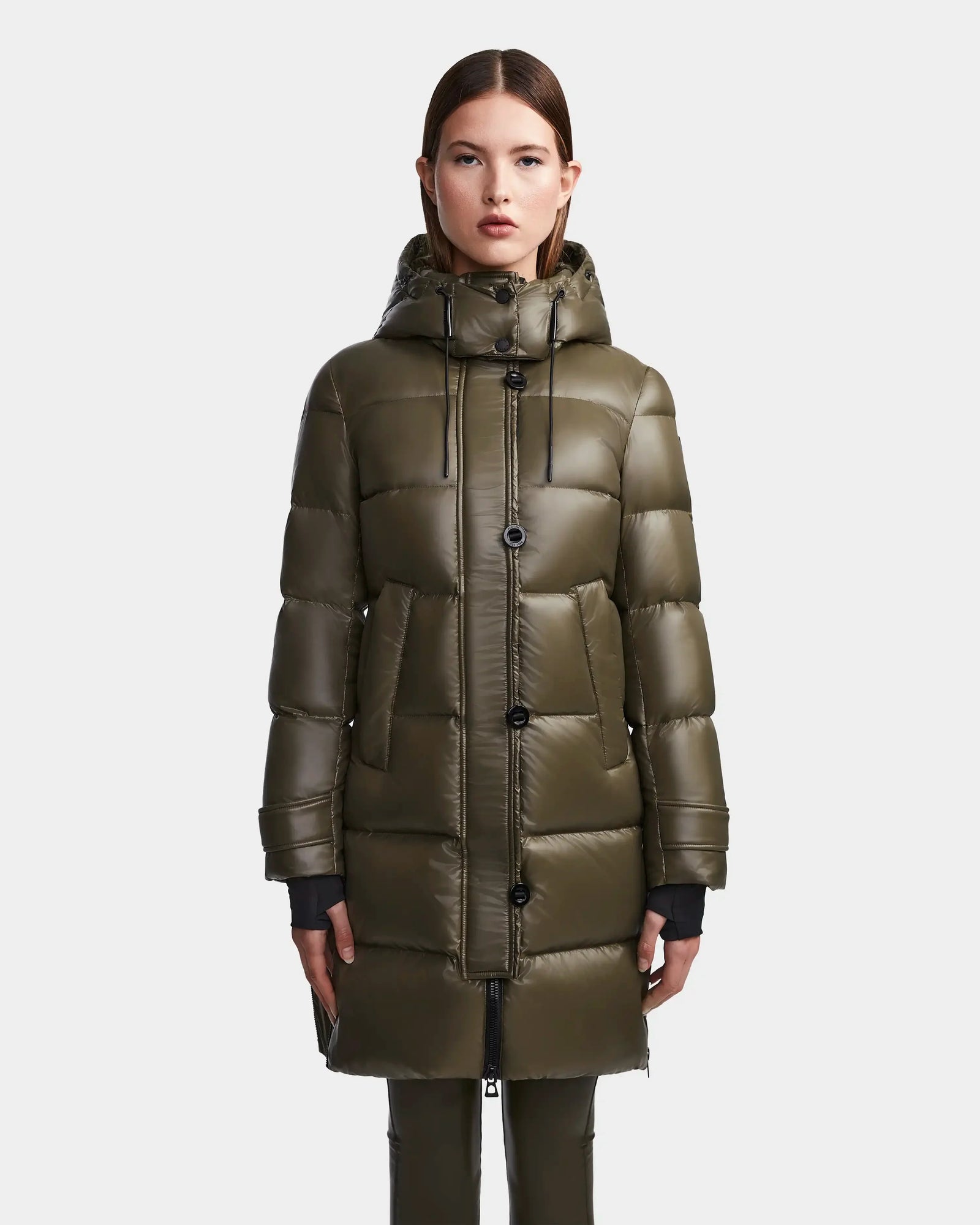 A woman faces forward against a plain light background, wearing the Rudsak MEYA S - L123521 Light Olive women's quilted down puffer with a removable hood, large buttons, and deep front pockets.