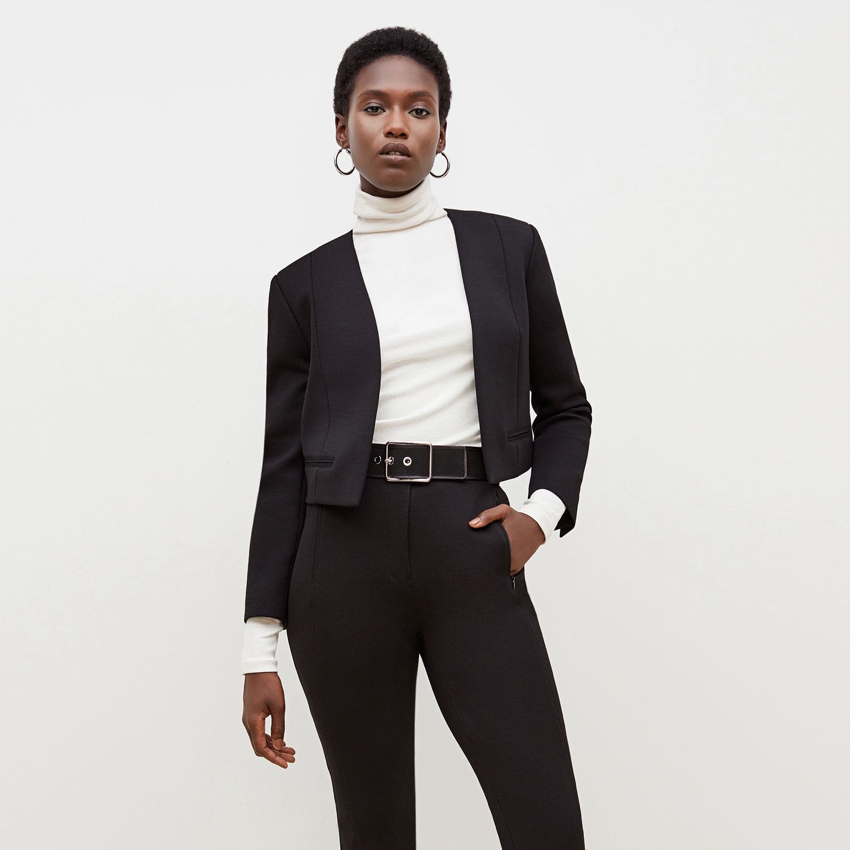 Front image of a woman standing wearing the Curie Pant--Worth in Black | Exclude