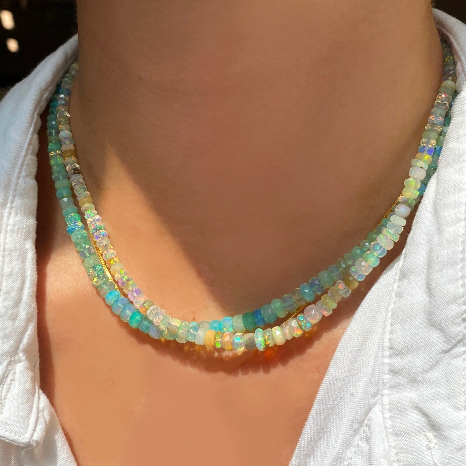 Shimmering beaded necklace made of faceted opals in shades of Blue, Teal, green and pale blue on a gold linking ovals clasp Styled on a neck layered with the Natural-Multi Faceted Opal Necklace