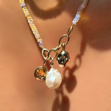 Natural multi faceted opal necklace with triple link charm lock dropping molten solitaire charm with round citrine, molten skull charm, and mini baroque pearl charm on the neck.