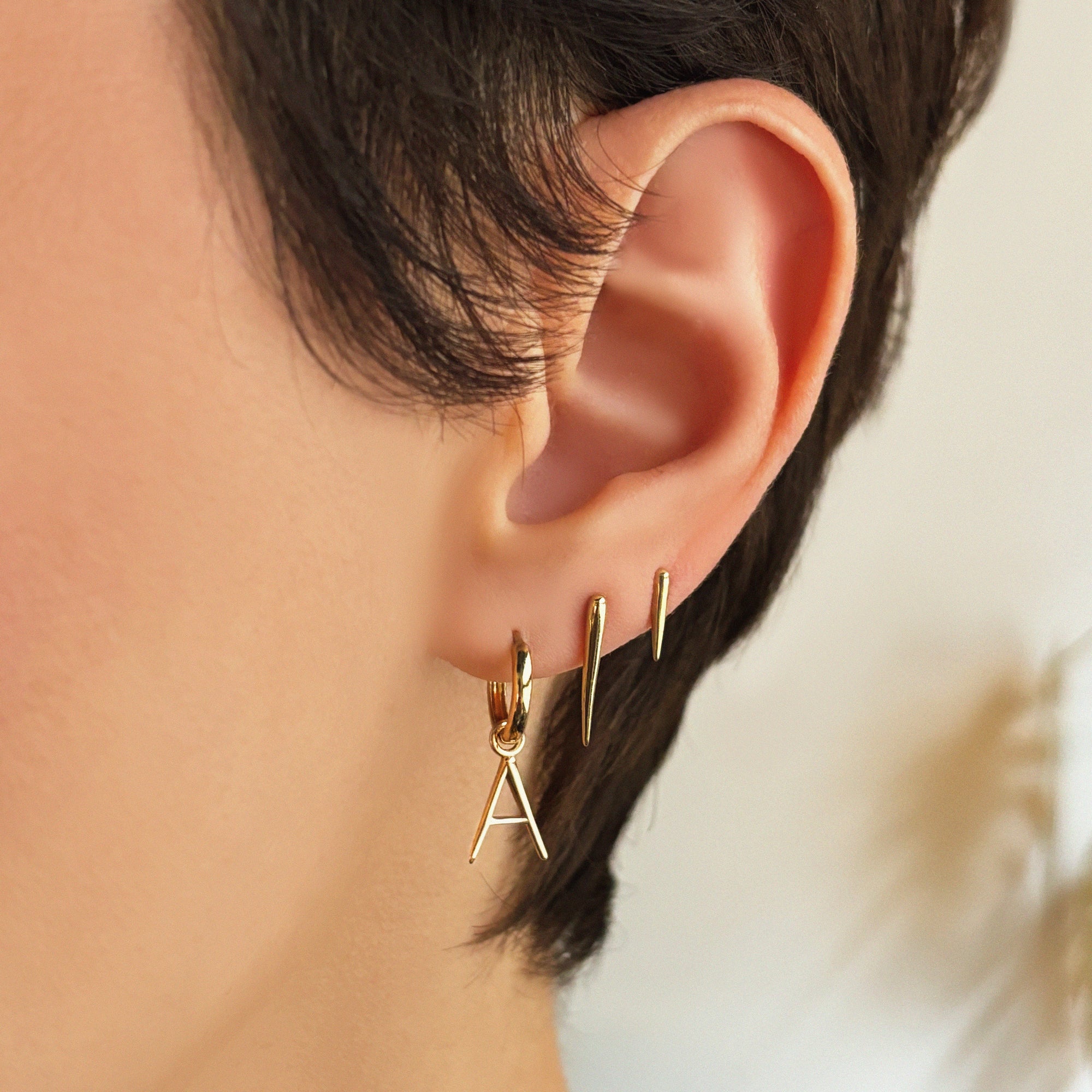 14k recycled gold Small Quill Spike Stud styled on a ear with the medium quill spike and letter "A" Huggie