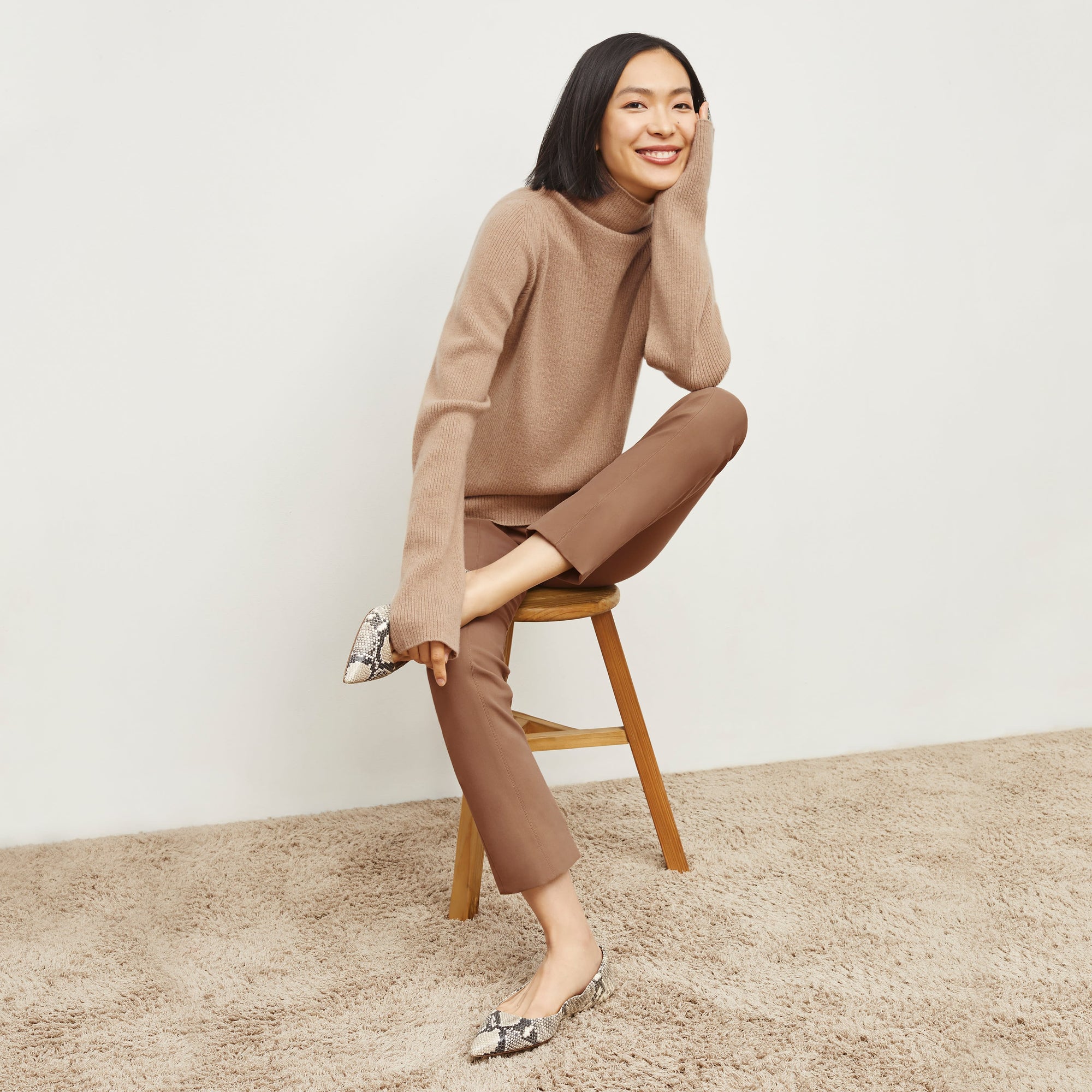 Front image of a woman sitting wearing the Foster Pant—Everstretch in Saddle | Exclude